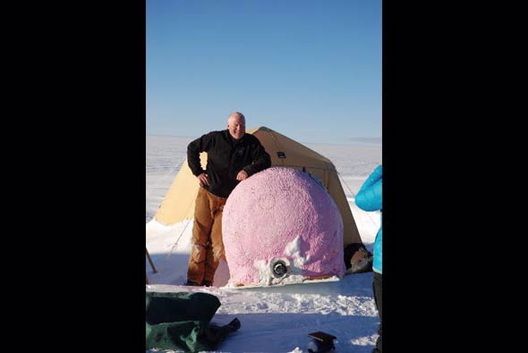 Mike standing outside his tent next to the large water container designed like a pink pig
